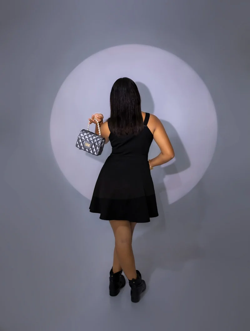 Retrato de espaldas con vestido negro e iluminación circular.